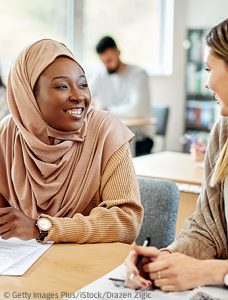 Zwei junge Frauen in einem Klassenraum sprechen miteinander