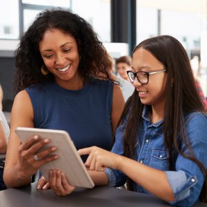 Eine Lehrerin bespricht etwas mit einer Schülerin. Sie schauen dabei auf ein Tablet.